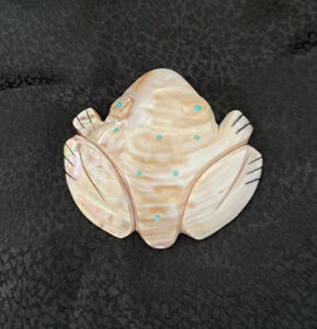 A carved pink mussel shell frog fetish inlayed with stabilized turquoise dots to add texture on back and for the eyes.
